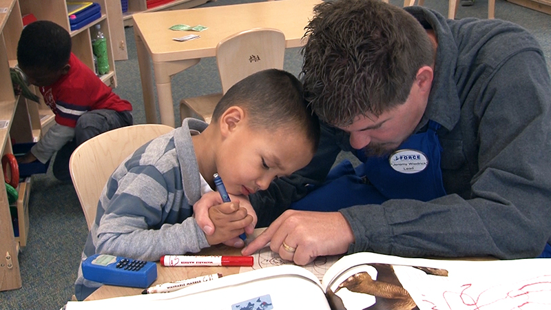 Preschooler coloring with Teacher