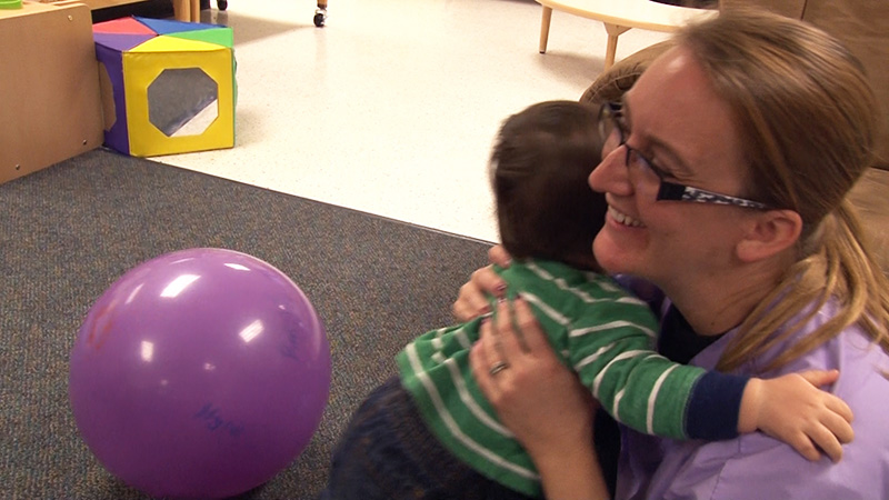 A staff member gets a hug from a toddler