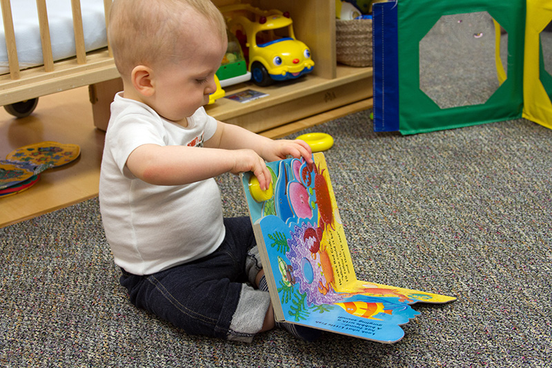 An infant plays with a book