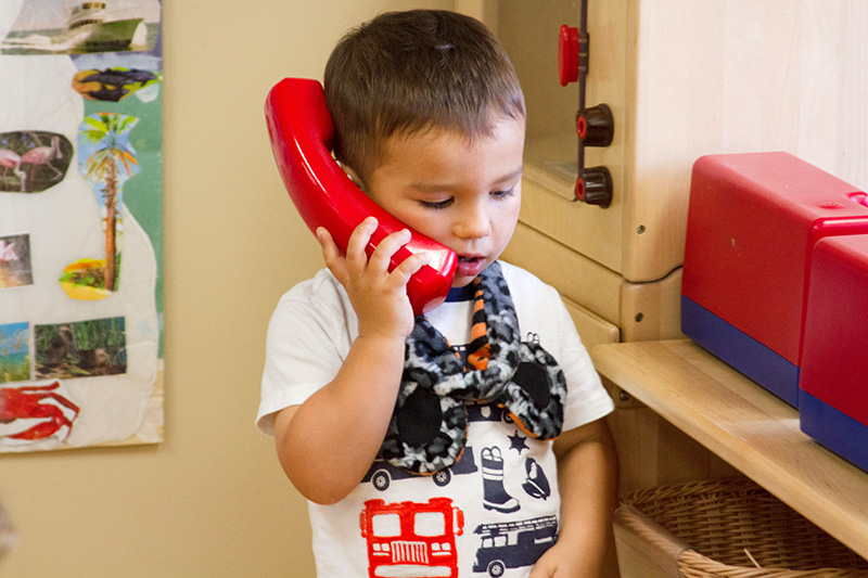 A toddler pretends with a play phone