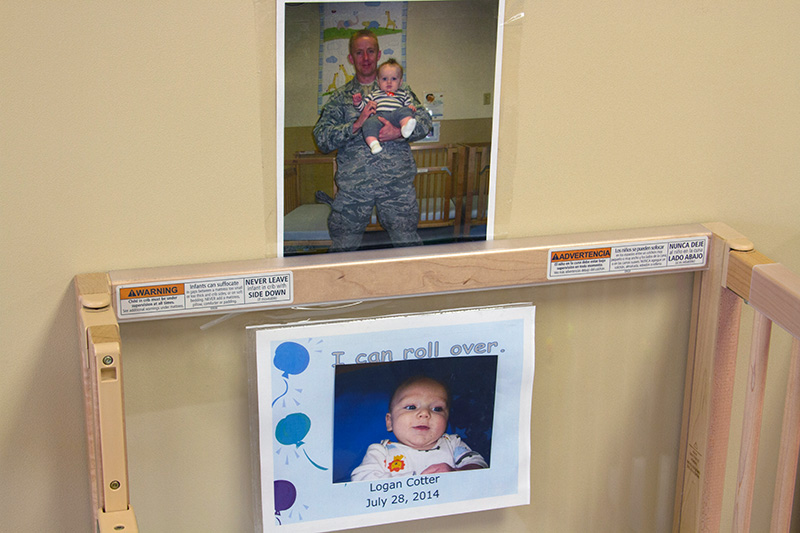 Photos of an infant and his parents are posted by his crib in a center