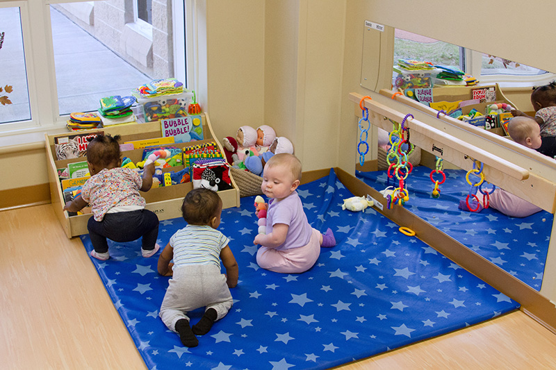 Infants play with toys on a blanket in a center