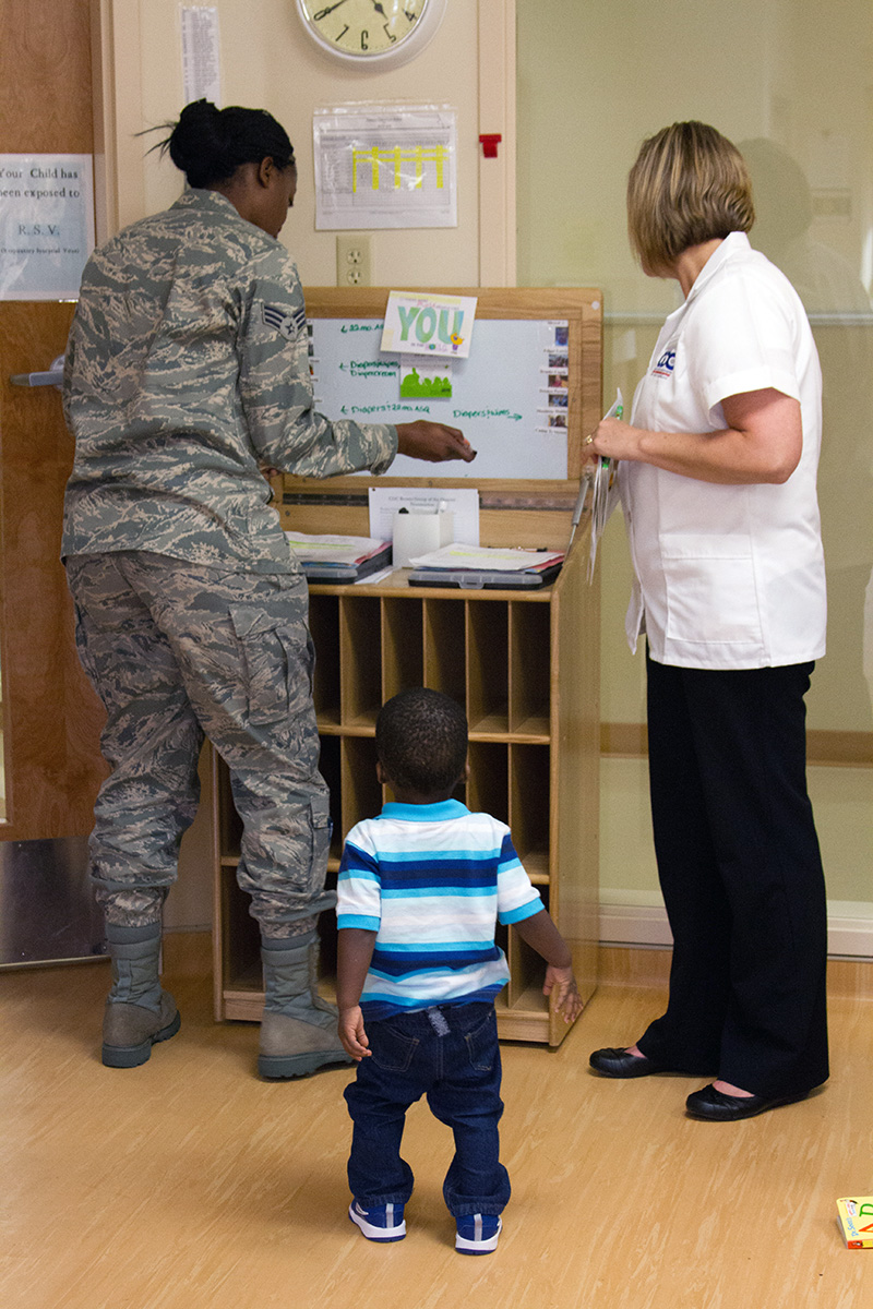 A parent and caregiver share information while the toddler watches