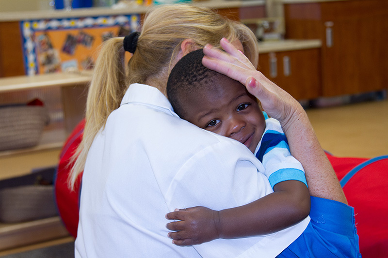 A caregiver hugs a toddler