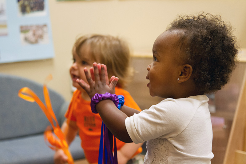 A toddler claps her hands