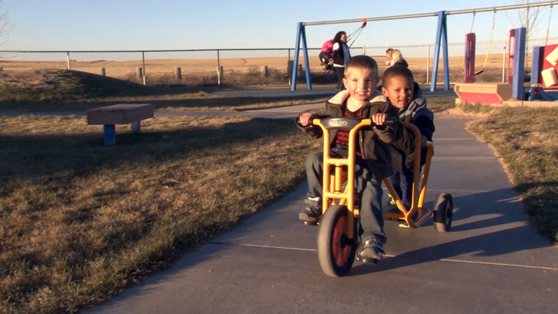 Preschool boys ride a tricycle
