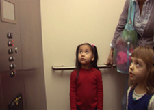 Children are accompanied by an adult in an elevator